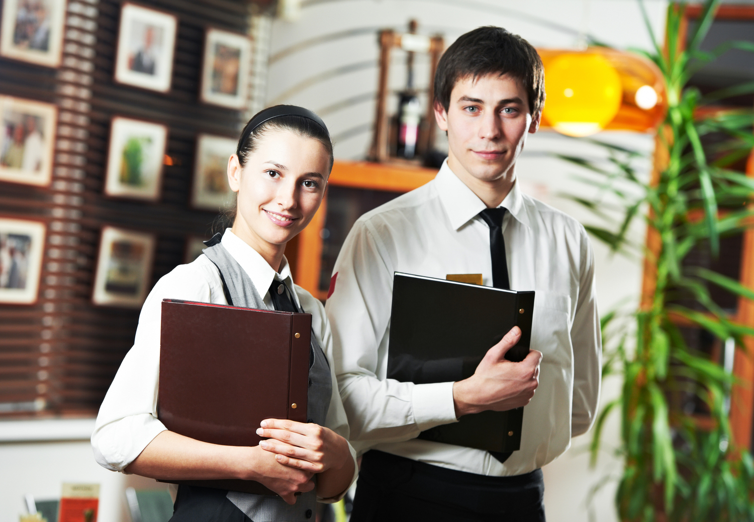 Waitress girl and waiter man of commercial restaurant in uniform waiting an order with menu